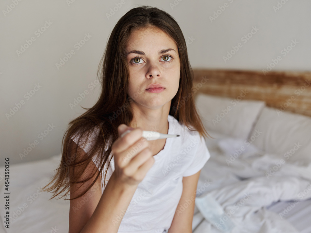 woman sitting on bed thermometer in hands pensive look woman sitting on bed thermometer in hands pensive look