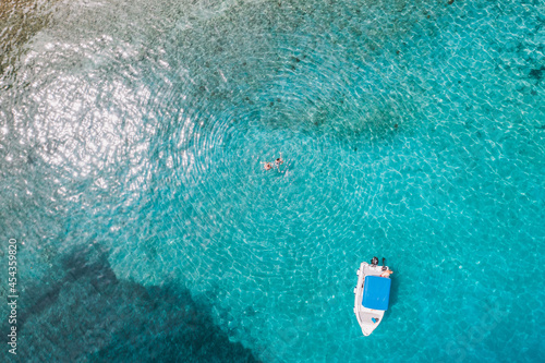 Boat in crystal clear water with people swimming