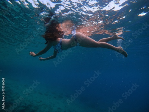 Mujer nadando bajo el agua en vestido de baño