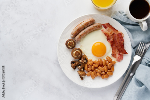 Horizontal of classic irish morning breakfast. Tasty keto diet meal. Sausages, mushrooms, kidney beans, eggs, bacon, orange juice and coffee on white background. Irish cuisine. Copy space