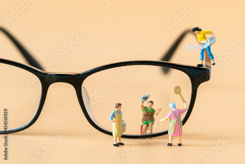 Miniature people Housewife Maid or Worker standing and cleaning dirty reading glasses using as Hospitality Hotel cleaning service business or health care healthy and wellness life style safety concept