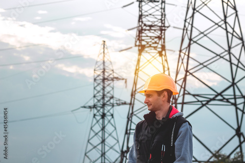 Worker in a helmet against the background of a substation and high-voltage poles