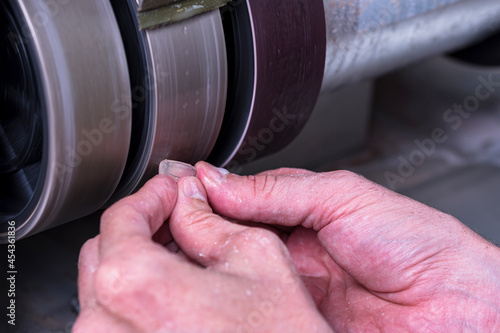 Craftsman preforming white transparent gemstone into the oval cabochon form