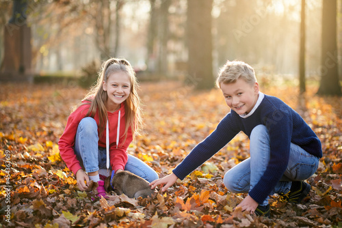 Sister and brother playing with dog in autumn forest. Concept family weekend. © serhiibobyk