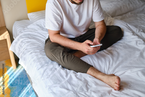 A man holds a smartphone in his hands in bed and checks a social network account before going to bed or after waking up. Gadget addiction. Man sending a text message on a mobile phone © Iuliia Pilipeichenko