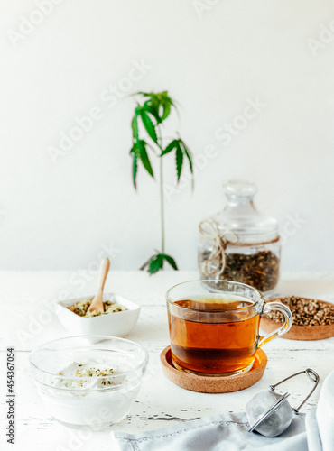 Hemp products: herb tea dry and fresh made in cup, seeds shelled and whole, yogurt with seeds, cannabis plant photo