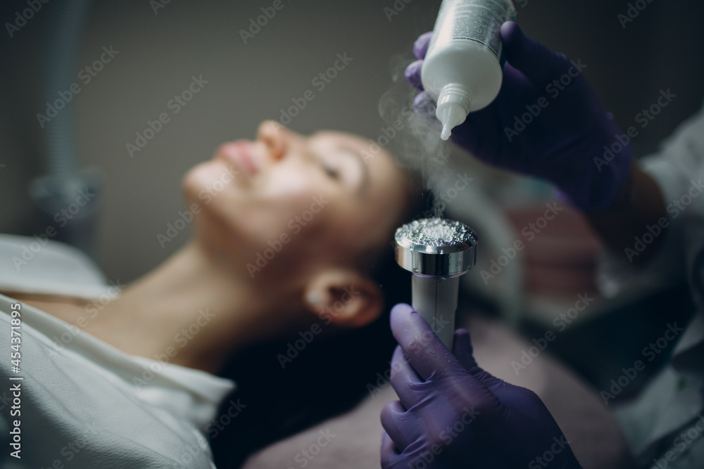 Close up of head woman receiving electroporation phonophoresis facial therapy at beauty spa salon