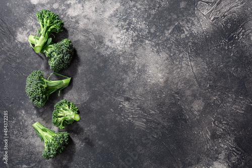 Broccoli flower heads atop dark textured backdrop, copy space, top view