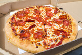Delicious pepperoni pizza in a folding cardboard box. Tasty fast food takeout to-go.