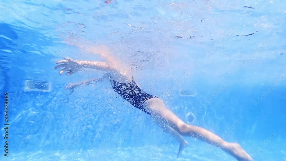 Adorable little girl swimming at outdoor swimming pool, underwater slow motion view Adorable little girl swimming at outdoor swimming pool, underwater slow motion view