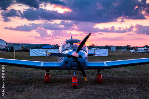 Sports aircraft parked at the airfield at picturesque sunset. Front view