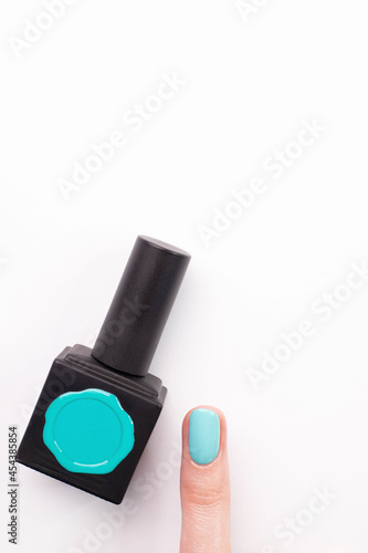 Turquoise manicure, blue nails, nail polish in a black jar on a white background, beauty salon, master, fingers