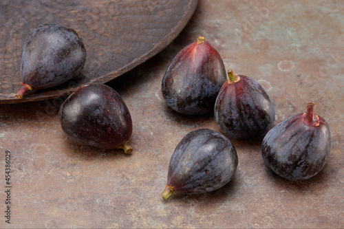 Ripe delicious figs with a bowl on an old wooden background. Food Photo. Whole fresh figs on rustic background. Selective focus