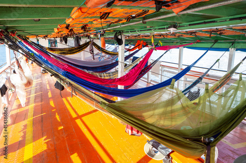 Colorful hammocks on Amazon Rainforest wooden boat in sunny summer day. Alter do Chão, Para, Brazil. Concept of nature, conservation, environment, ecology, vacation, tourism, travel.