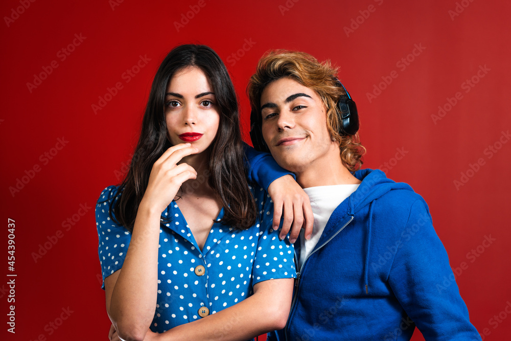 Young stylish couple wearing blue clothes standing on the red background Young stylish couple wearing blue clothes standing on the red background