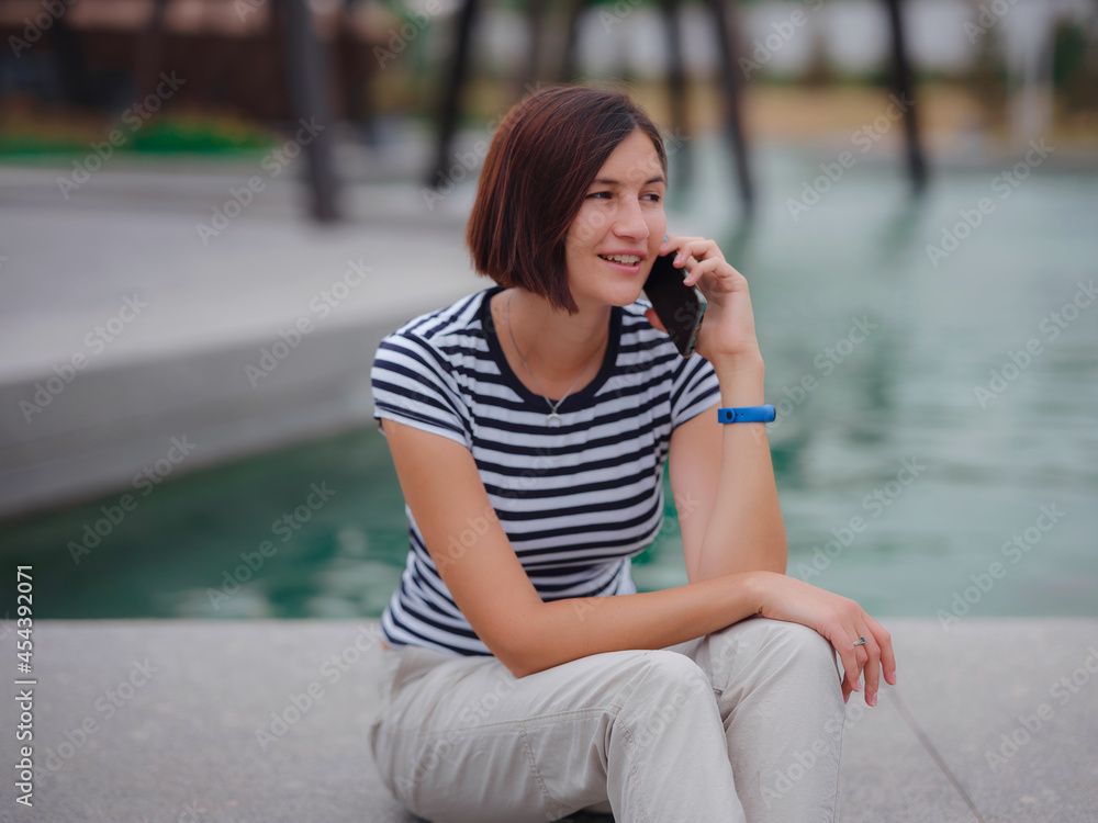 Portrait of beautiful asian young woman in park with smartphone. Smartphone summer asian woman talking on mobile phone Portrait of beautiful asian young woman in park with smartphone. Smartphone summer asian woman talking on mobile phone