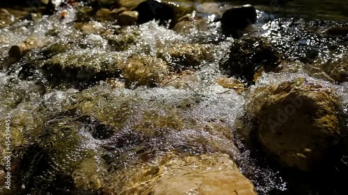 A small stream, filmed in slow motion, the back light from the sun creates beautiful glares and glitters upon the bubbly water. Kziv River, Israel. photo