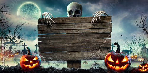 Fotografie, Obraz Halloween Card Party - Pumpkins And Zombies In Graveyard With Wooden Board