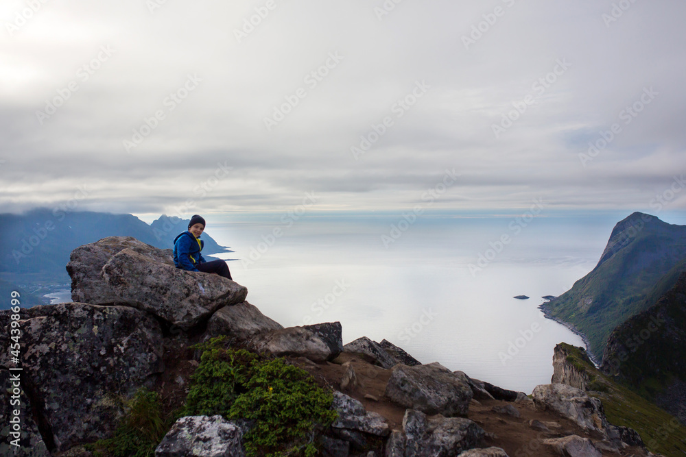 Cute child, standing on a rock and looking over Segla mountain on Senja island, North Norway. Amazing beautiful landscape and splendid nature in scandinavian country