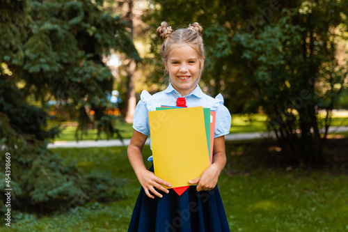 Happy schoolgirl holding a book outdoors. A small child goes to school. Copy space. photo