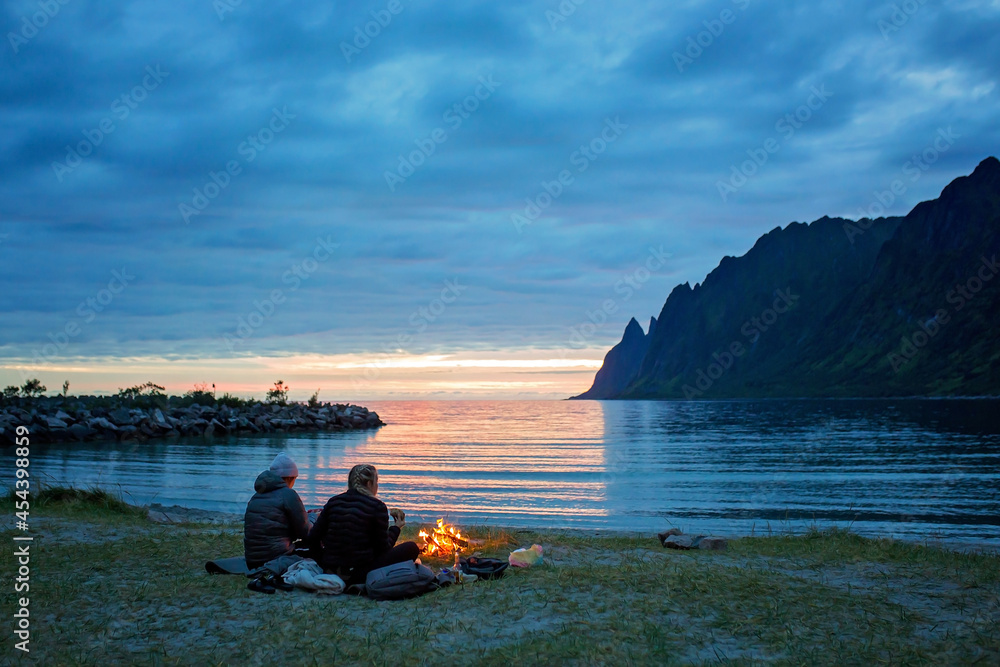 People, enjoying fireplace on the beach, wild camping on Ersfjord beach in Senja national park in  northern Norway