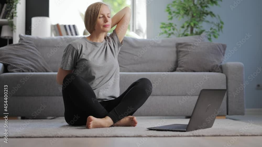 Attractive woman with blond hair using wireless laptop while training at home. Caucasian female watching online tutorial during domestic workout. Attractive woman with blond hair using wireless laptop while training at home. Caucasian female watching online tutorial during domestic workout.