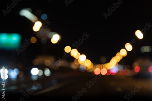 Night illumination lights over a wet road. Bokeh holiday lighting. Black background © Naletova
