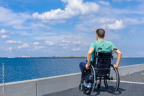 Disabled man in a wheelchair at the sea. Travel, mobility and freedom concept.