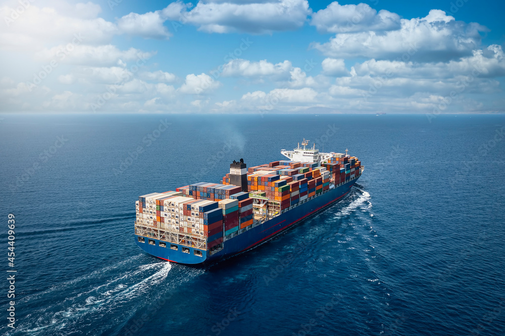 A large container cargo ship travels over calm, blue ocean - obrazy, fototapety, plakaty 