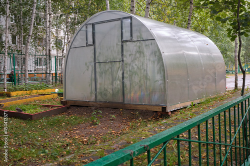 Handmade greenhouse from a metal framework and a polyethylene film on a farmer's land plot. Greenhouse Hotbed for vegetable seedlings.