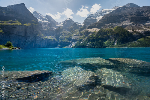 Des rochers en transparence sous un lac bleu transparent au milieu des montagnes alpines