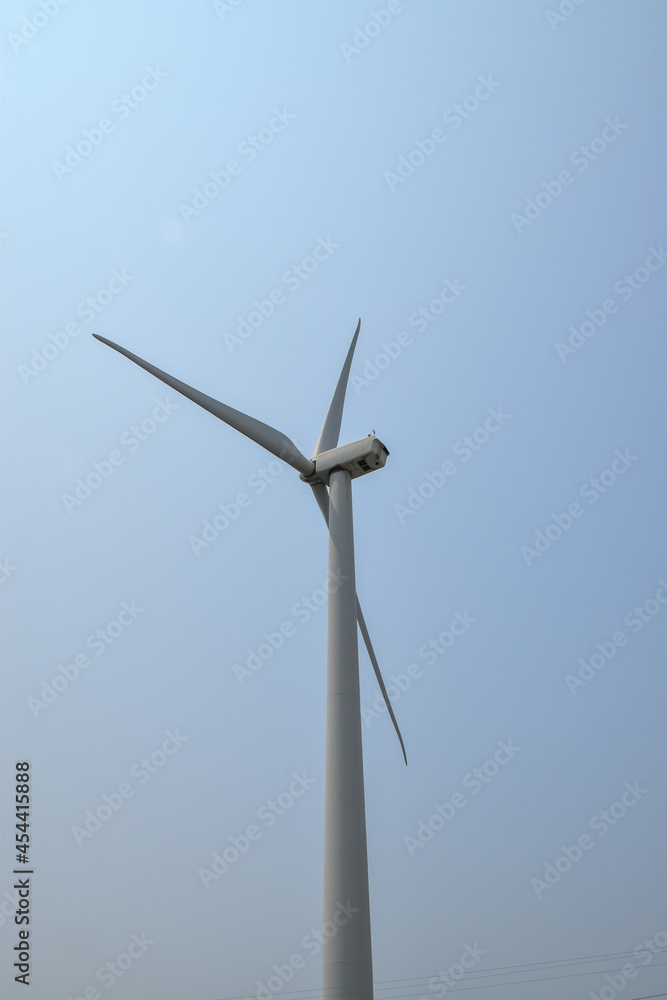 Close up view of the top of a wind turbine with three blades against a clear blue sky Close up view of the top of a wind turbine with three blades against a clear blue sky