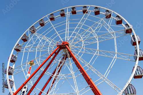 Ferris wheel turns on a sunny day at amusement park. No people