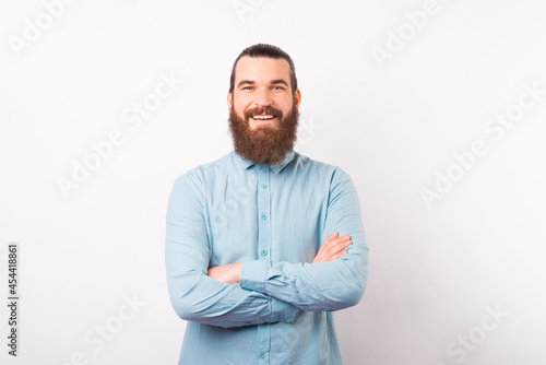 Portrait of a young confident bearded man is smiling at the camera over white background.