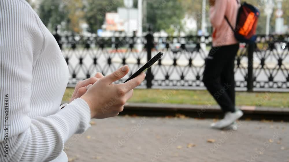 Close up of woman hands using a smart phone searching content on the street, side view Close up of woman hands using a smart phone searching content on the street, side view
