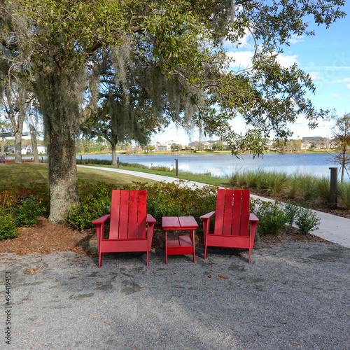 Two chairs sitting in a park by a lake in Laurete Park in Lake Nona, Orlando, FL on a beautiful sunny day. photo