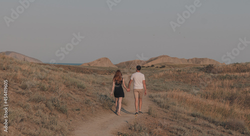 Couple of a man and a girl walking through a field, view from the back