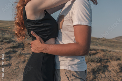 A couple in lovers. The guy hugs the girl around the waist, the girl hugs the guy around the neck.