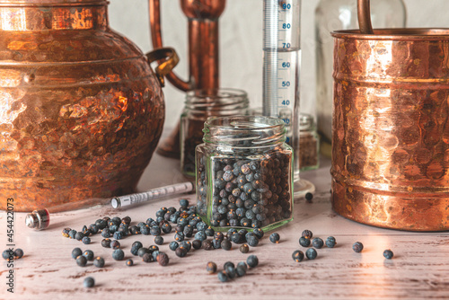 Photos Enebros en primer plano junto a un Alambique de cobre utilizado para destilar con botánicos, enebro, cardamomo y accesorios sobre una mesa de madera