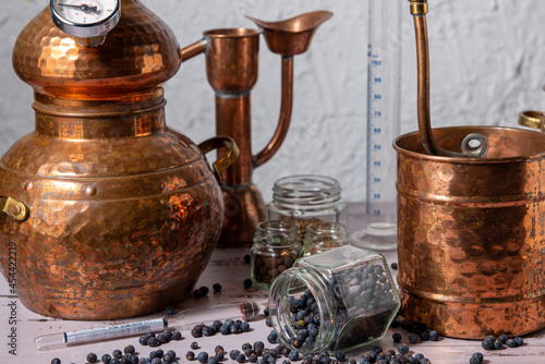 Photos Alambique de cobre utilizado para destilar con botánicos, enebro, cardamomo y accesorios sobre una mesa de madera