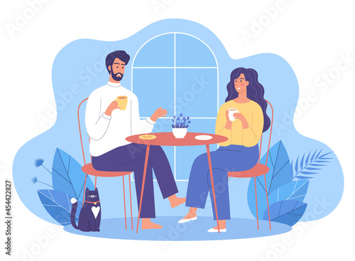 Cute young couple woman and man drinks some tea at home with their cute cat