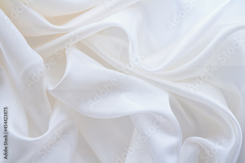 diaphanous white fabric draped with folds, textile wave background photo
