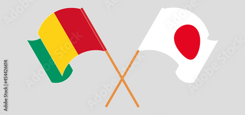 Crossed and waving flags of Guinea and Japan