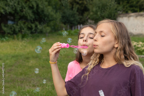 Two girls blowing soap bubbles - carefree and fun time and friendship