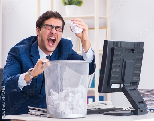 Young handsome businessman employee working in office in paperwo photo