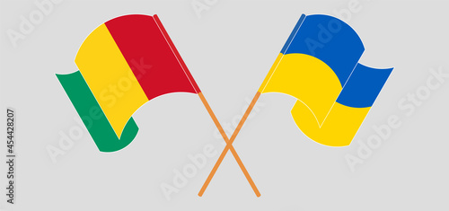 Crossed and waving flags of Guinea and Ukraine