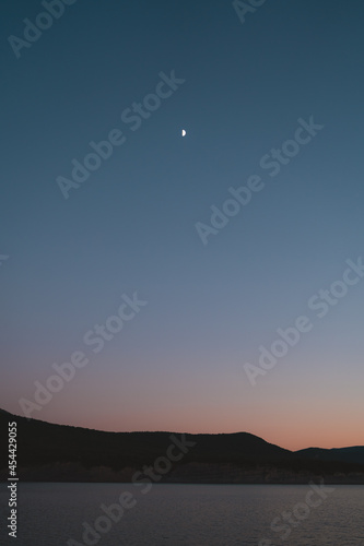 Crescent moon over the hills around Yesa lake during twilight