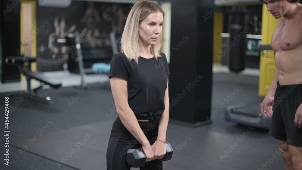 Woman exercising with trainer. The male instructor observes the correct execution of the exercise. Woman exercising with trainer. The male instructor observes the correct execution of the exercise.