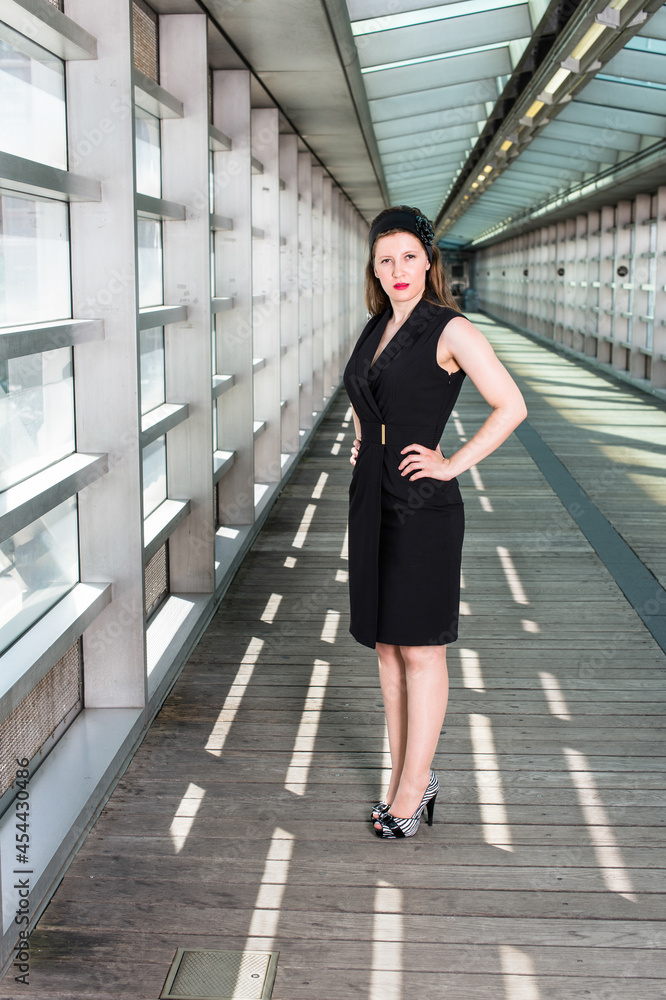 Dressing in black sleeveless clothes a beautiful woman is confidently standing in a walkway. Dressing in black sleeveless clothes a beautiful woman is confidently standing in a walkway.