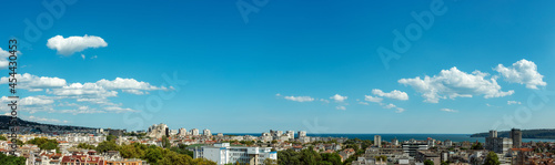 Clear azure summer sky with few white fluffy clouds over seaside town. Pleasant mild september weather in the subtropical climate. Sunny panoramic landscape of Varna. Wide image.